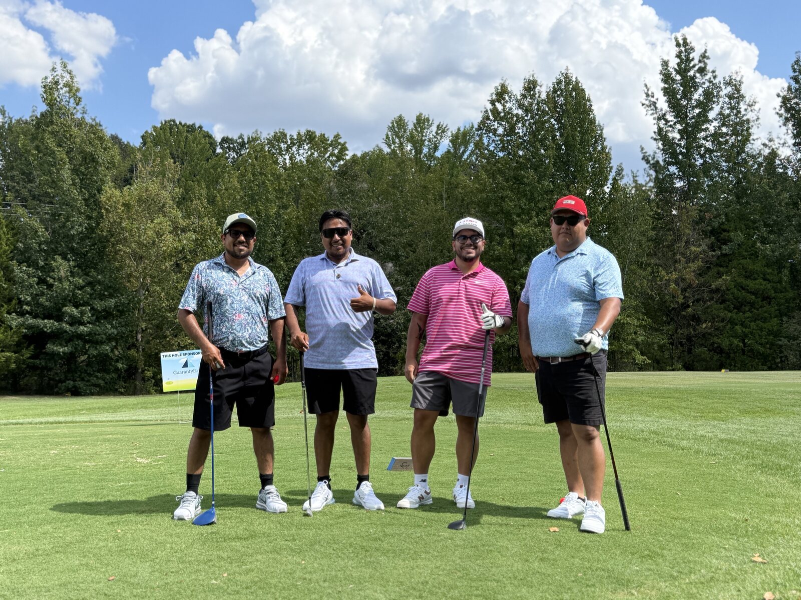 Four golfers standing together on the course at the scholarship tournament