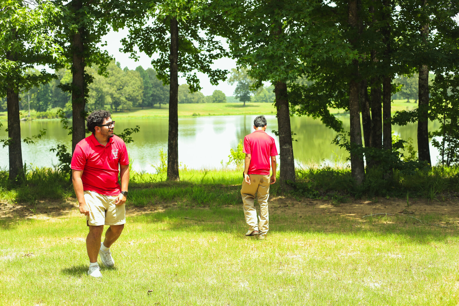 Two people in red shirts outdoors near a lake at the event